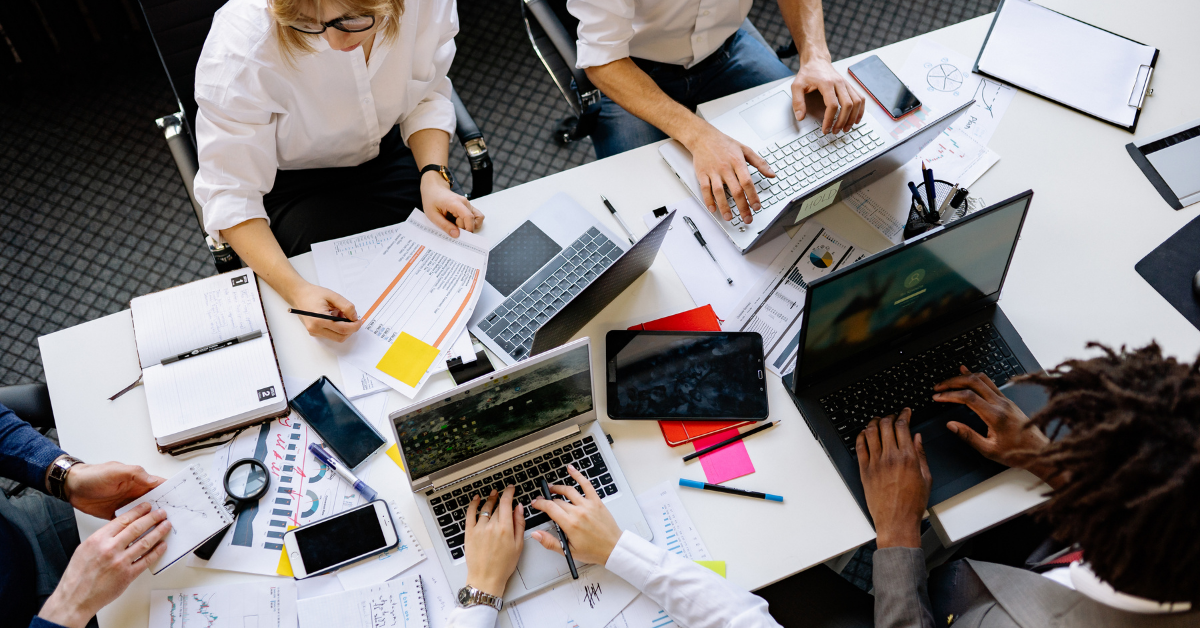 People working at desks on laptops and looking at paperwork