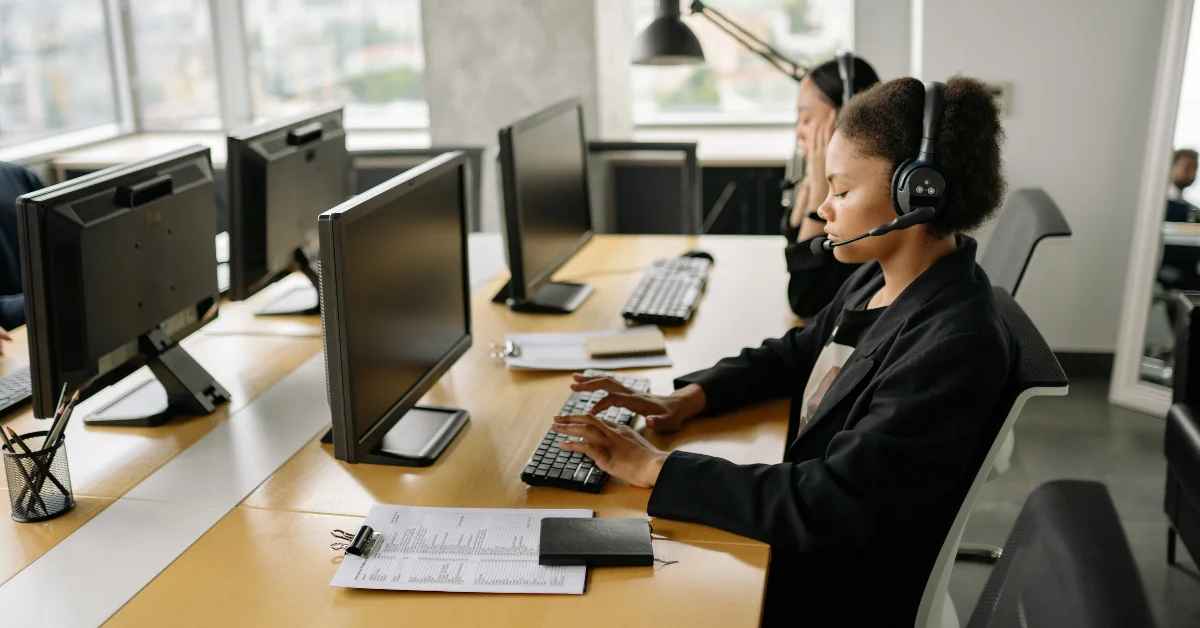 two women at call center hearing headsets at desks
