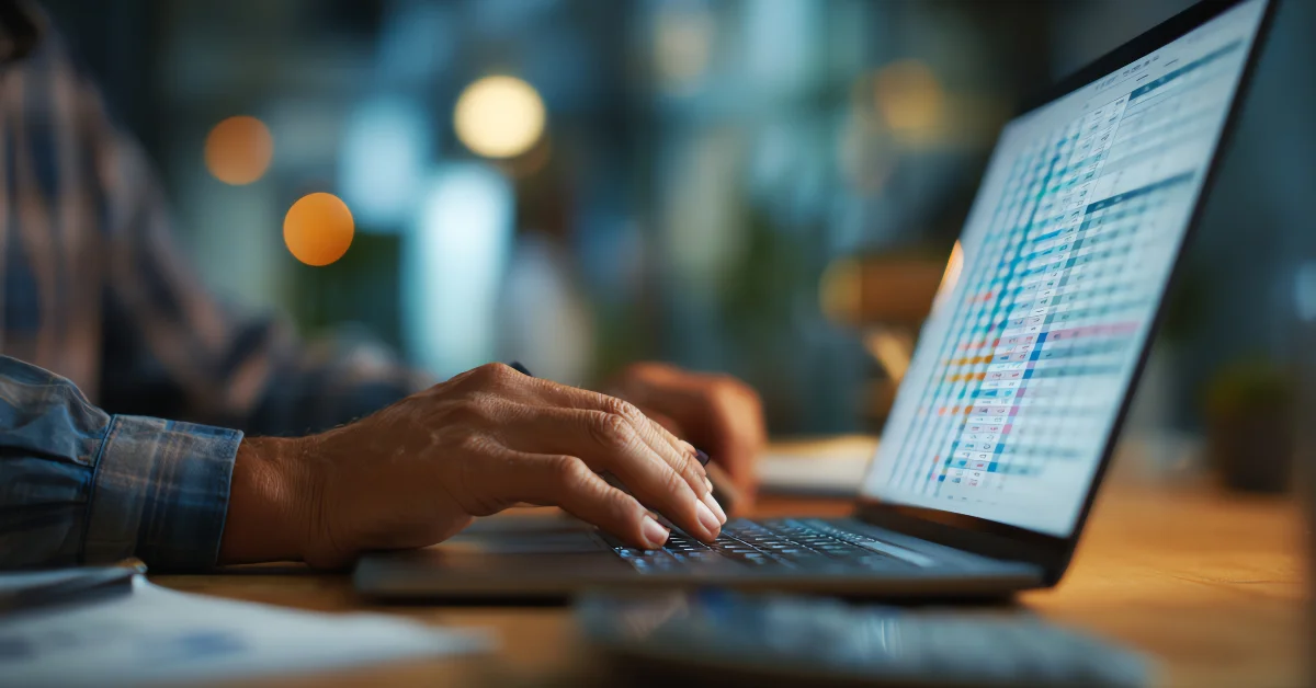 typing on laptop with spreadsheet open